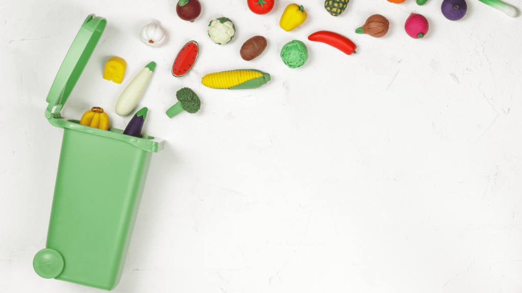 Cubo de basura del que salen frutas y verduras volando/flotando